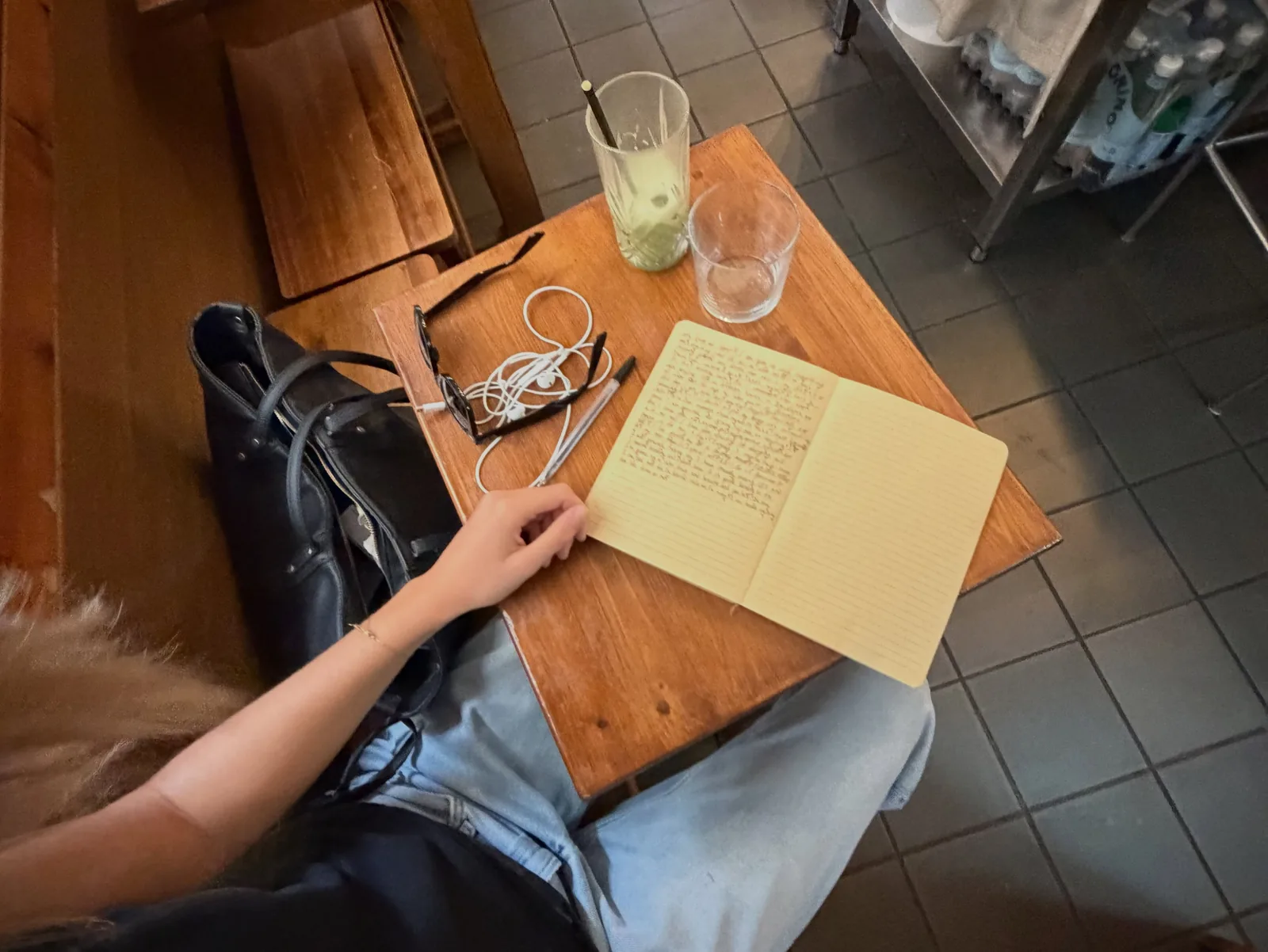 Her hands on a wooden table, an iced matcha and an open notebook