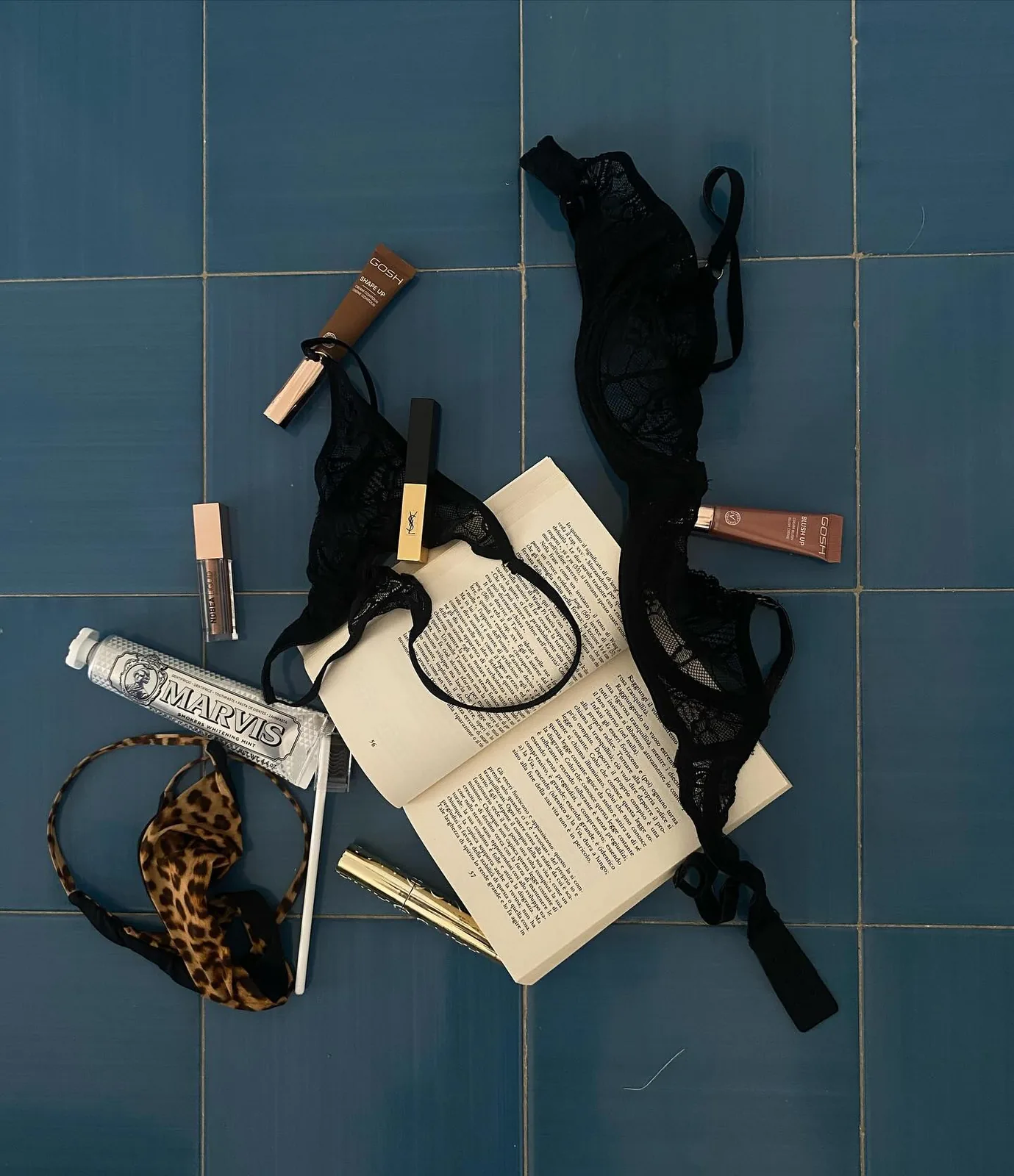 Lingerie, a book, Marvis toothpaste and lipsticks on blue tiles