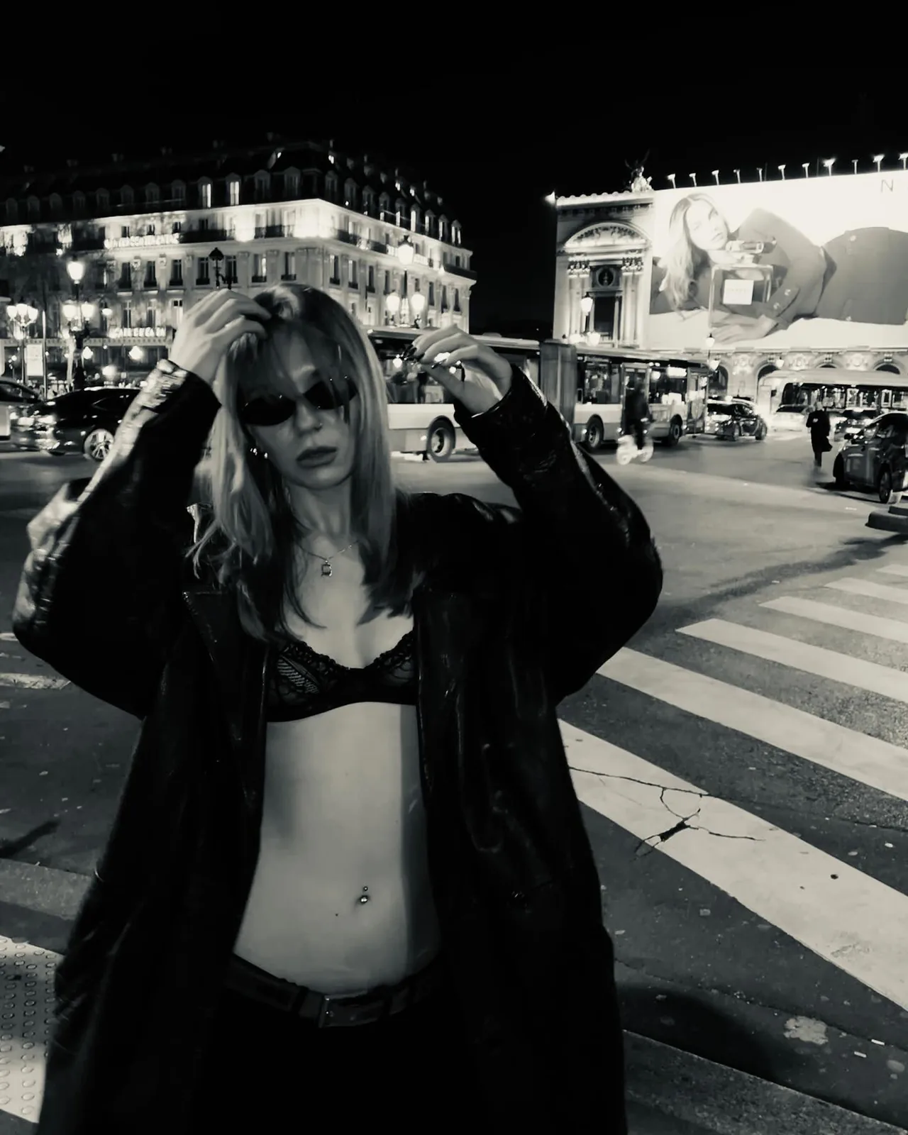sofia crossing a Paris street at night in an open black coat, black and white